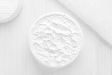 Pure white moisturizer in a white jar.  Cotton sponges. White towel.