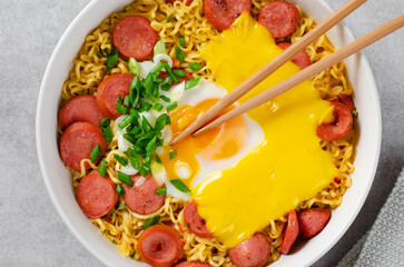 Ramen Noodles with Sausages, Egg, Melted Cheese and Scallion, Microwave Shin Ramyeon or Ramyun on Bright Background