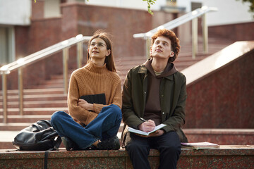 Looking up. Man and woman students are together outdoors near university
