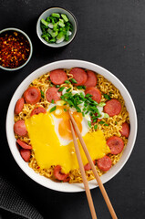 Ramen Noodles with Sausages, Egg, Melted Cheese and Scallion, Microwave Shin Ramyeon or Ramyun on Dark Background