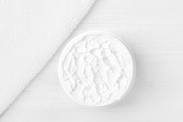 Pure white moisturizer in a white jar.   White towel.