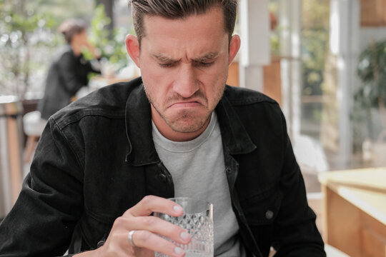 Unhappy Man With Sad Face Looking Down At An Empty Glass 