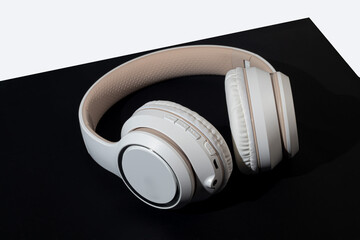 Beige wireless headphones on a dark background. Accessory for listening to music. Isolate.