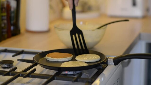 woman cooking pancake with kitchen spatula on pan