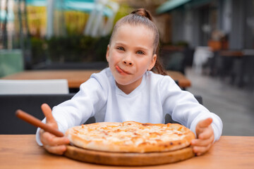 girl eating pizza in pizzeria. child with her tongue out in anticipation