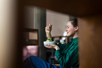 Young woman eating salad in an office. - Powered by Adobe