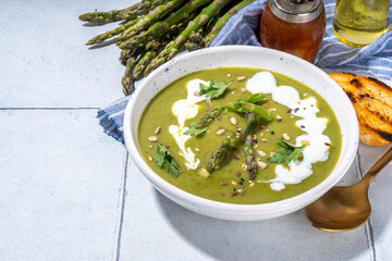 Homemade green asparagus cream soup, with sour cream, fresh asparagus decor and croutons 