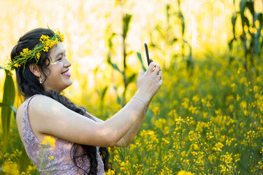 Foto de mujer hablando selfie en celular mientras camina en campo ,bosque,amarillos ,flores,atractiva