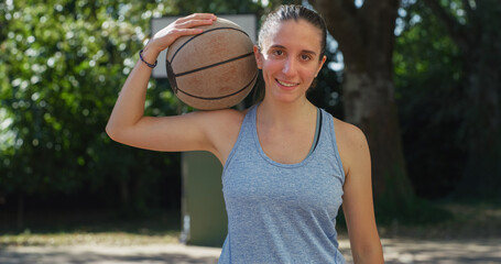 Portrait of Beautiful Young Woman Holding Basket Ball, Looking at the Camera and Smiling in Outdoor...