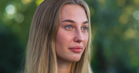 Fototapeta premium Portrait of Beautiful Caucasian Young Woman Smiling with a Greenery Background. Happy Blond Female Teenager Enjoying Fresh Air in the Park and Taking Care of her Wellbeing