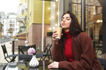 Beautiful woman on the terrace of a cafe enjoying the aroma of delicious coffee. coffee love