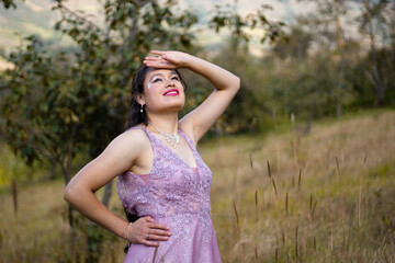 Hermosa chica sonriente con un vestido en el campo puesta la mano sobre la cabeza,estilo de...