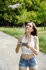 Cheerful woman outdoors in nature controlling camera drone with remote control