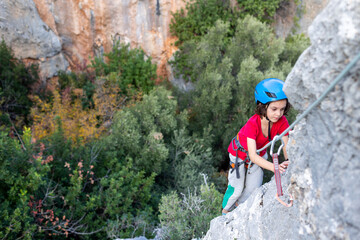 Naklejka na ściany i meble climber boy. the child trains in rock climbing.