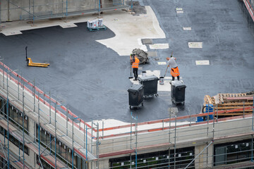Roofer painting flat roof of a commercial building..