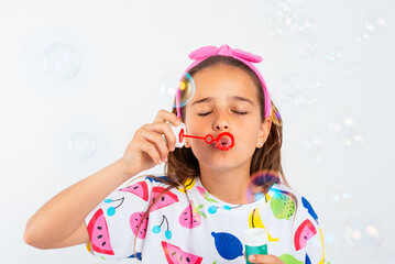 Little girl blowing bubbles in water of soap