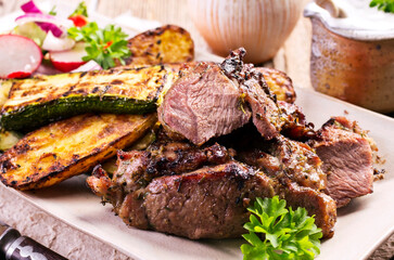 Traditional barbecue lamb roast with grilled vegetable and lettuce served as close-up on a design plate