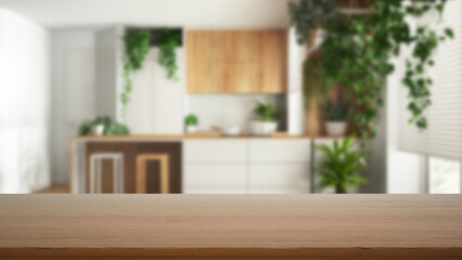Fototapeta na wymiar Empty wooden table, desk or shelf with blurred view of minimal white and wooden kitchen with island and many houseplants. Urban jungle interior design concept