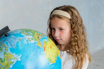 primary schoolgirl looking at globe. geography interesting learning.concept of save the world and learn through play activity for kid education at home.lovely girl in classroom