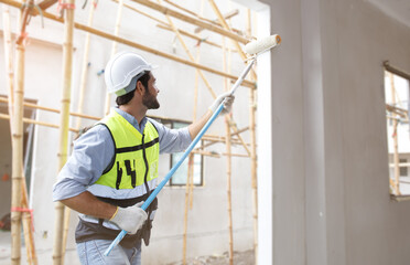 Male painter with paint roller forward on the construction site White primer on concrete walls standing at the construction of modern buildings