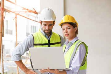Team of industrial engineers men and women wearing helmets discussing new projects. while using laptop