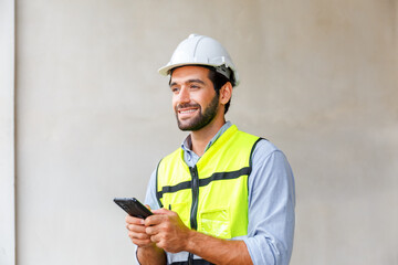 Male engineer in green reflective vest and hard hat using phone construction worker communication