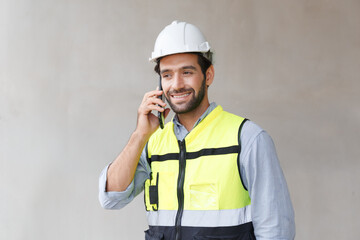 Male engineer in green reflective vest and hard hat using phone construction worker communication