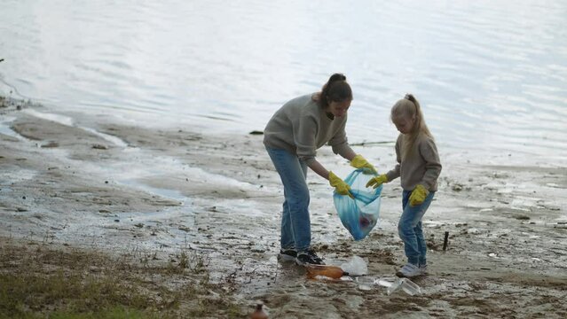 Family Of Volunteers Collecting Plastic Waste From Lakeshore, Mother And Daughter, Ecology Concept