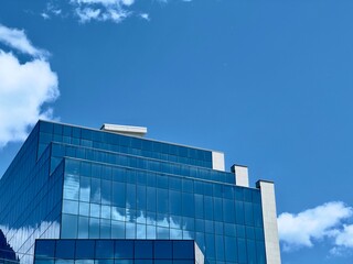 Modern Glass Tower with a Stunning Blue windows and White Clouds reflections in the Sky