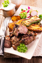 Traditional barbecue lamb roast with grilled vegetable and lettuce served as close-up on a design plate