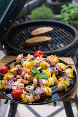 ready to eat - grilled shrimps with salmon and vegetables on a black plate, from a bbq grill at a...