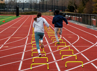 Fototapeta premium Two runners running over six inch mini hurdles on a track