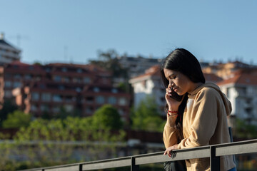 Worried woman walking and writing or reading sms messages online on a smartphone while the wind moves her hair on a street