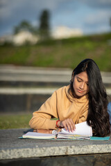 overwhelmed young woman studying outside college or high school campus with her notes in blue folder