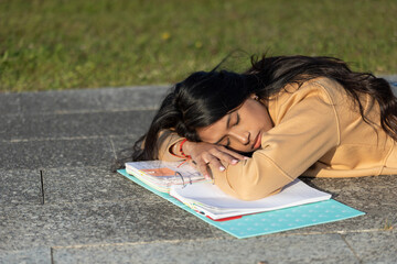 a young woman falls asleep studying in her blue folder outside of campus, high school or university