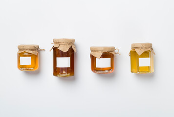 Jars with different honey on white background, top view. Mock up design