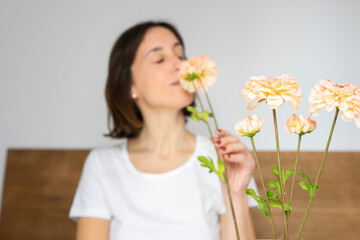overjoyed girl sitting in bed having breakfast, smelling the flowers