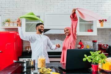 happy middle-eastern married couple spending time together at home and wearing traditional arab...