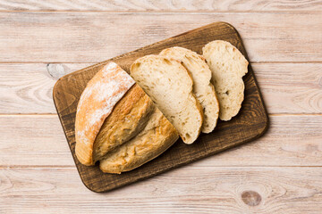 Freshly baked bread slices on cutting board against white wooden background. top view Sliced bread