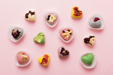 chocolate sweets in the form of a heart with fruits and nuts on a colored background. top view with space for text, holiday concept