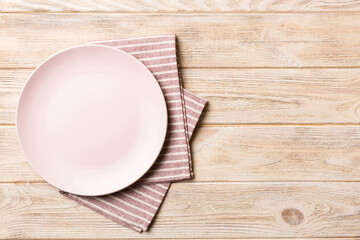 Top view on colored background empty round pink plate on tablecloth for food. Empty dish on napkin with space for your design