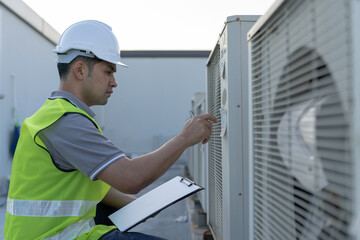 Asian maintenance engineer works on the roof of factory. contractor inspect compressor system and...