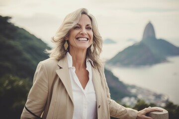 Portrait of beautiful mature businesswoman smiling and looking away while standing on top of mountain in morning