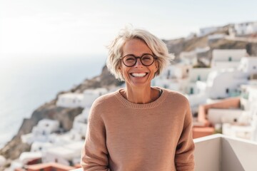 Fototapeta na wymiar Portrait of a smiling senior woman with eyeglasses looking at camera in Santorini