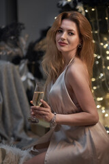 Sexy middle aged woman model with a glass of champagne at a party drinking champagne on a holiday glowing blue background. Confident modern lady at a night party