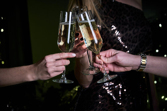 Female Friends Make Toast As They Celebrate At Party. Group of partying girls clinking flutes with sparkling wine