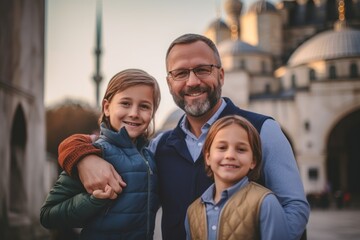 Obraz premium Portrait of happy family. Father and children are standing in front of the mosque.