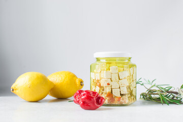Marinated feta cheese cubes in olive oil in a glass jar. Cheese cubes marinating in olive oil, feta...