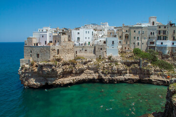 Casco histórico de Polignano a Mare sobre un acantilado de piedra caliza en Italia. Casas al sur de la cala Monachile sobre el mar Adriático con aguas turquesas un soleado día de verano.