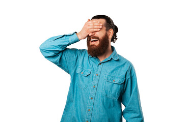 Handsome bearded man is giving himself a face palm gesture over white backdrop.
